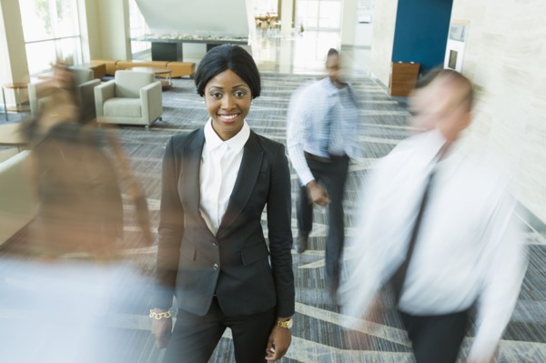 Businesswoman standing still in busy office lobby