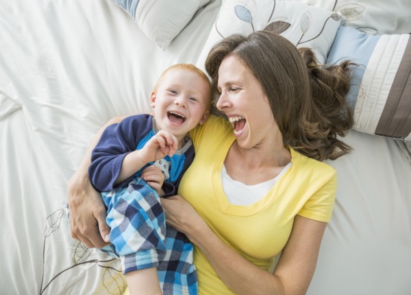 Caucasian mother and son playing on bed