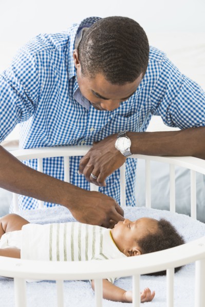 Father admiring sleeping baby son in crib