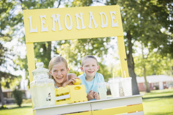 Caucasian brother and sister smiling at lemonade stand