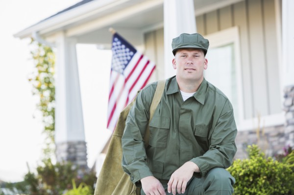 Caucasian soldier kneeling near house