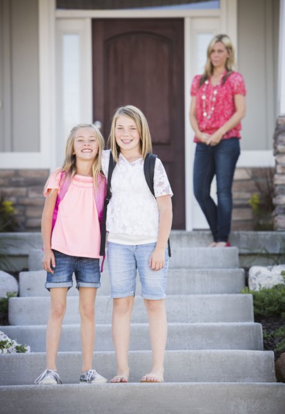 Caucasian sisters smiling on front steps on way to school