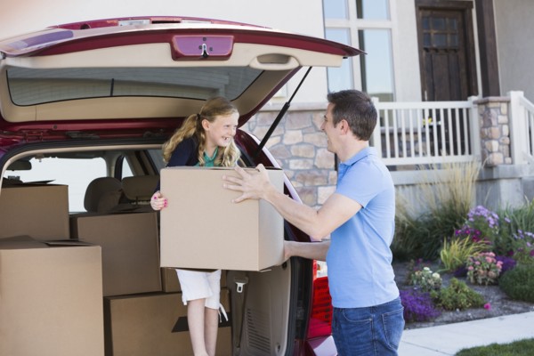 Caucasian family unpacking cardboard boxes from car