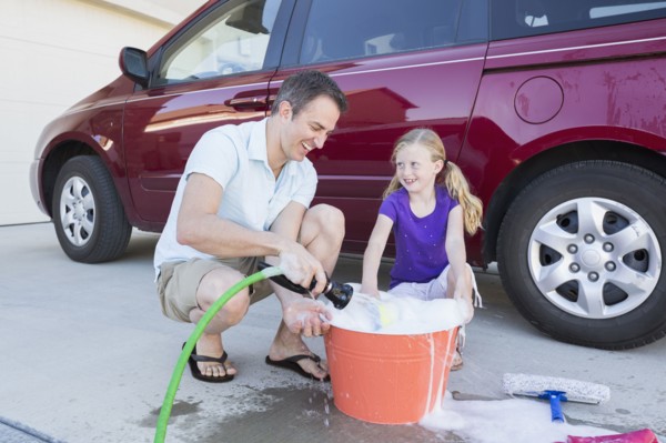 Caucasian father and daughter washing car in driveway