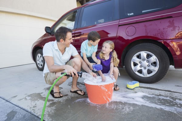 Caucasian father and children washing car in driveway