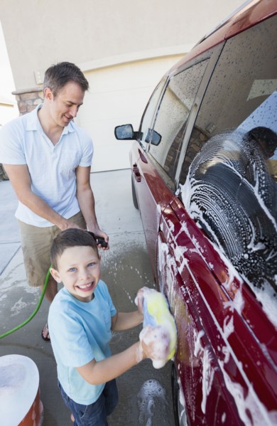 Caucasian father and son washing car in driveway