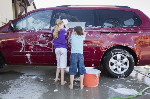 Caucasian children washing car in driveway