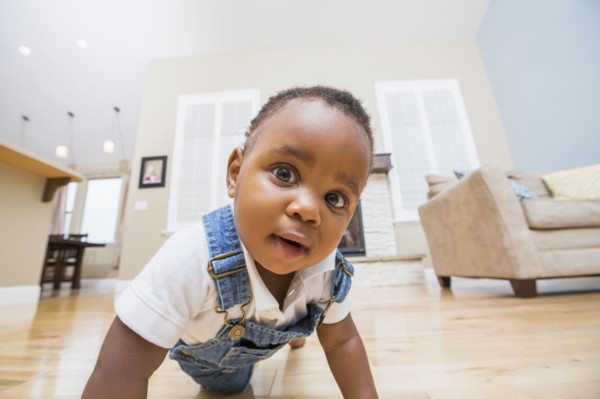 Black baby crawling on living room floor