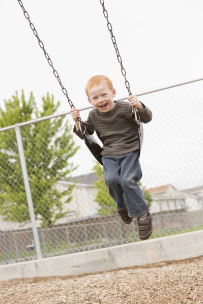 Caucasian boy sitting on playground swing
