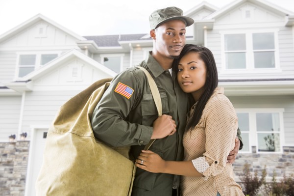 Returning soldier and wife standing outside house