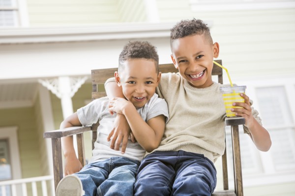 Brothers hugging in armchair in backyard