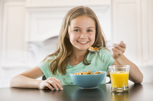 Caucasian girl eating cereal at table