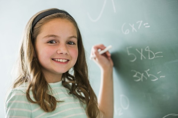 Caucasian girl doing math problems on chalkboard