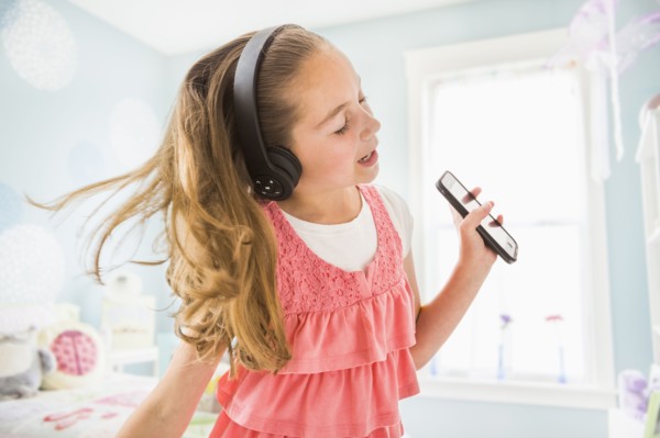 Caucasian girl singing to wireless headphones