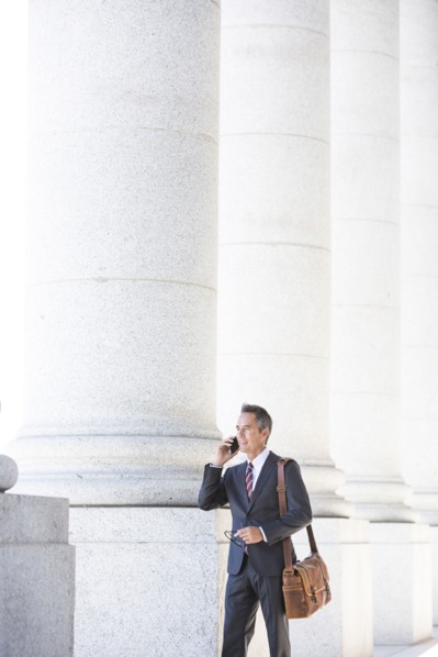Mixed race businessman talking on cell phone under columns