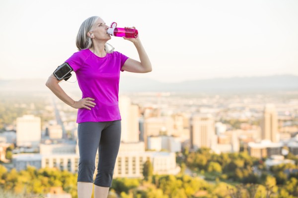 Caucasian woman drinking water bottle on urban hilltop