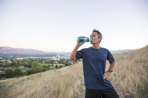 Mixed race man drinking water bottle on hilltop
