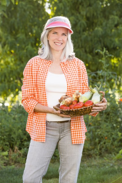 Caucasian woman holding basket of vegetables in garden