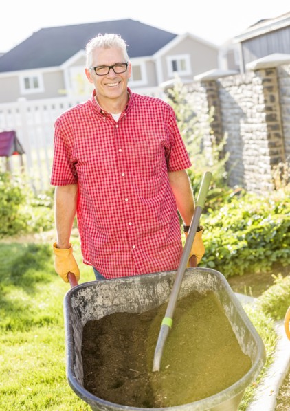 Caucasian man pushing wheelbarrow of dirt