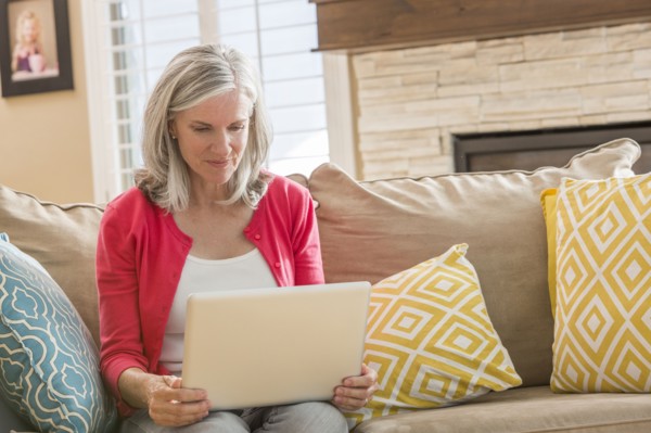 Caucasian woman using laptop on sofa