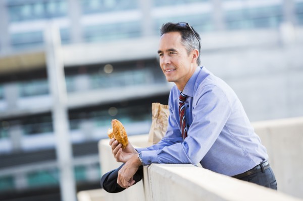Mixed race businessman eating on urban rooftop