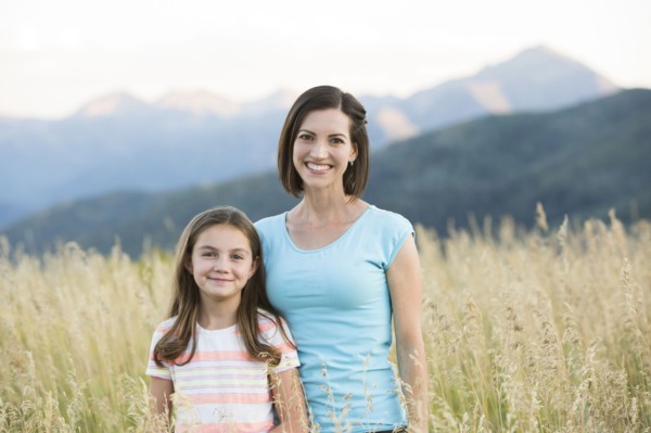 Caucasian mother and daughter smiling in field