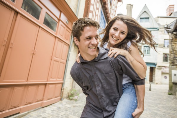 Caucasian man carrying girlfriend piggyback in village