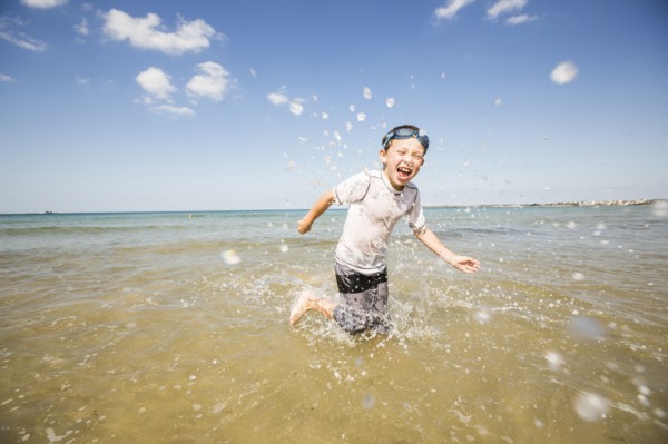 Caucasian boy splashing in waves on beach