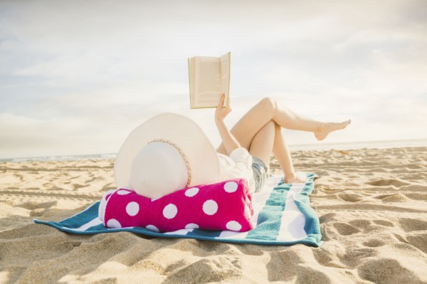 Caucasian woman reading book on beach