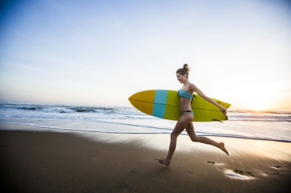 Caucasian woman carrying surfboard on beach