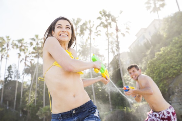 Caucasian couple playing with squirt guns on beach