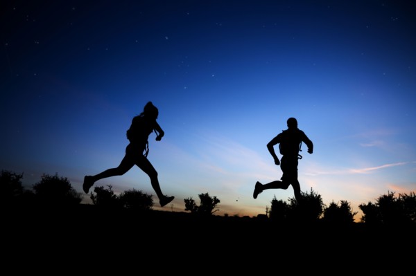 Silhouette of Caucasian couple running at dawn