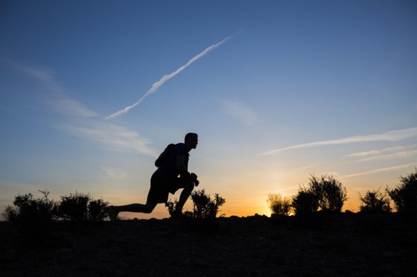 Silhouette of Caucasian teenage boy running at dawn