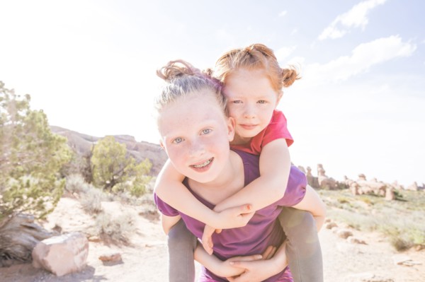 Caucasian girl carrying sister piggyback