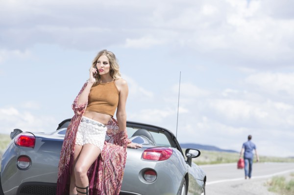 Caucasian woman talking on cell phone at vehicle breakdown