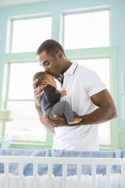 Black father kissing baby son on forehead