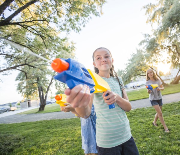 Caucasian girls playing with squirt guns