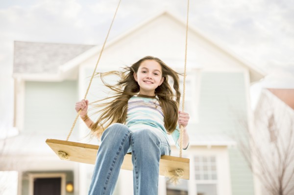 Caucasian girl on rope swing near house