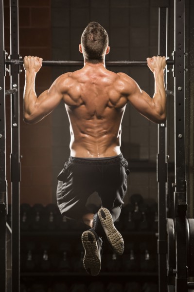 Caucasian man doing chin-up in gymnasium