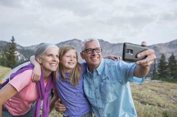 Caucasian grandparents and granddaughter posing for cell phone selfie