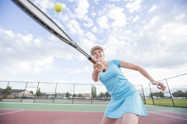 Caucasian woman hitting tennis ball