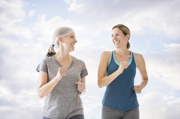 Smiling Caucasian women running against clouds