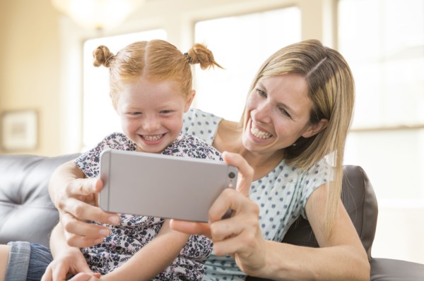 Caucasian mother and daughter posing for cell phone selfie