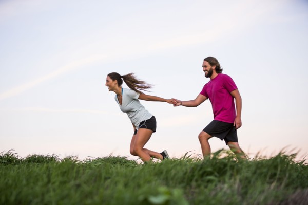 Caucasian woman pulling man on hill