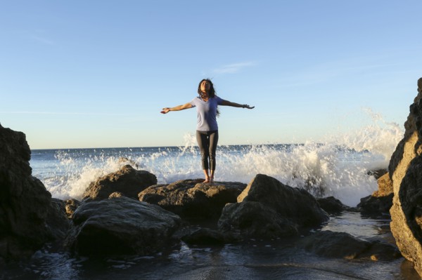 Asian woman standing on rock at beach