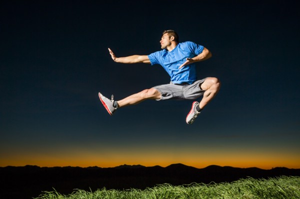 Caucasian man jumping at sunset