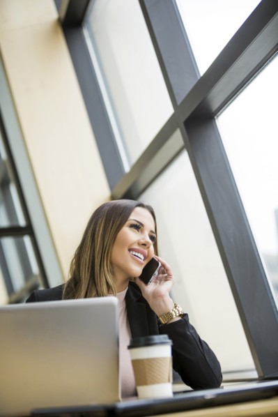 Mixed Race businesswoman talking on cell phone near laptop