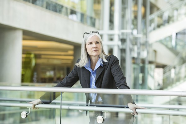 Portrait of serious Caucasian businesswoman leaning on railing in lobby