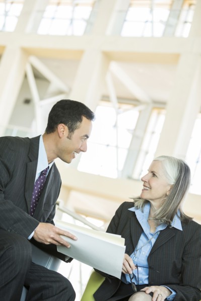 Smiling business people reading paperwork in lobby