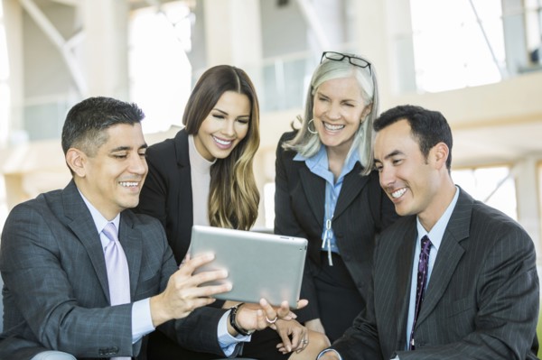 Smiling business people reading digital tablet in lobby